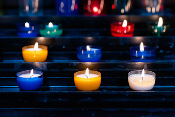 Illuminated atmosphere with colorful tealight candles on a shelf