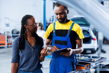 Mechanic in car service ordering new brakes for damaged vehicle using tablet. Licensed technician next to customer looking online for components to replace old ones in malfunctioning automobile