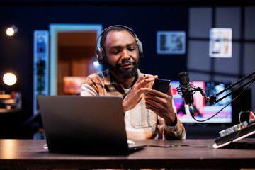 Portrait of black male influencer grasping mobile device and doing a review for online audience....