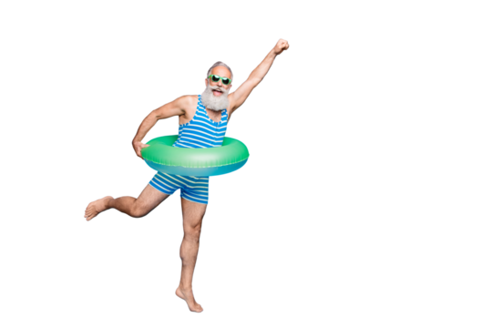 Full length photo of excited retired pensioner with grey hair raising his fist holding toy circle wearing striped swimwear glassses isolated over blue background