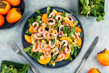 Healthy salad with shrimp prawns, persimmon and green salad.