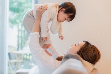 おうちで赤ちゃんに高い高いをするお母さん