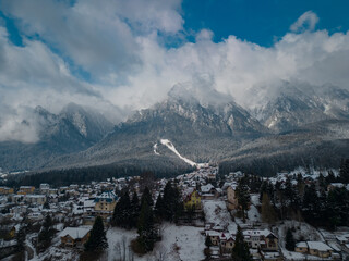 Picturesque winter landscape with high mountains covered in snow. Busteni, a small town at the foot of Bucegi Mountain seen from a drone on a snowy day