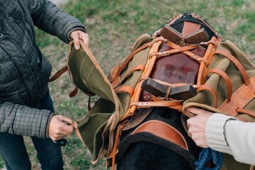 Two individuals diligently preparing a horses saddle and its gear, effectively showcasing their...