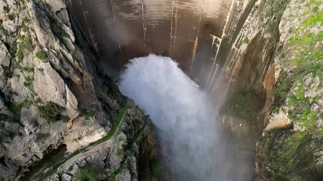 Dam discherge water. Slow motion overhead view of water outlet from the dam. Aerial view. Howell Bunger valve in operation in vault dam. Quentar Reservoir. Spain.