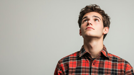 Obraz premium Thoughtful young man looking up in a checkered shirt