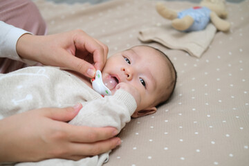 Infant baby asian boy is lying on the bed with pacifier. 