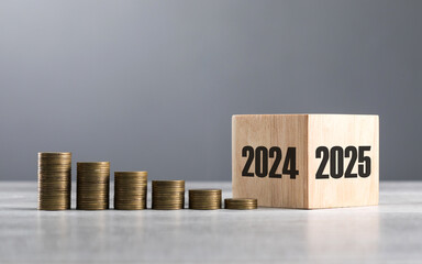 Wooden blocks transitioning from 2024 to 2025, accompanied by neatly stacked coins, symbolizing...