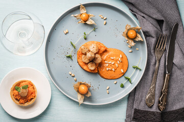 A gourmet scallops lunch with carrot puree in Romesco sauce served on a blue plate with fesalis, a...