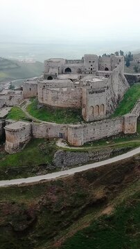 Wide aerial view of Krak of Chevaliers medieval castle in the Syrian mountains, vertical video.