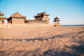 Chinese temple on the beach in Qinhuangdao, famous for having the beginning of the Great Wall of China, known as the Old Dragon Head. View from the sand at sunset.