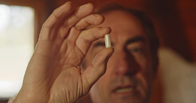 Close up of A man holding a white capsule filled with powder and talks about it. Drug enforcement concept