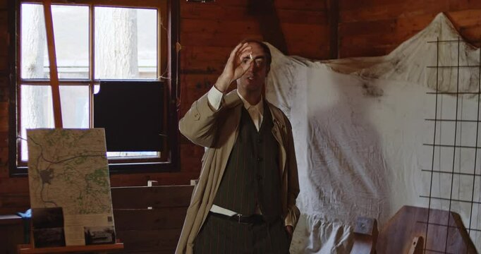 Wide shot of a World War 2 era spy giving a briefing in a hideout. The secret agent grabs a white capsule and talks about it. The man continues to throw the pill to someone else.