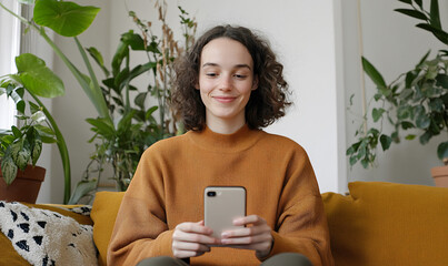 Woman using smartphone on a cozy sofa