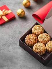 Fototapeta premium A beautifully wrapped box of Lunar New Year mooncakes, each intricately designed, set alongside festive red envelopes and gold ingots