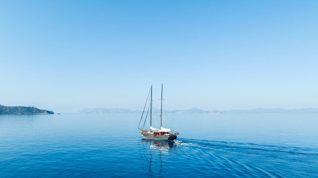 A gulet ship cruising through clear blue waters on a sunny day.gulet, sailing, blue sea, boat, ocean, travel, summer, sunlight, peaceful, nautical, vacation, scenic, coastal.