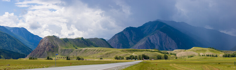 Panoramic summer landscape with Mount Belgebash hidden by thunderstorm rain gray clouds at Altai republic, Russia. Overcast view of the Altai steppe and Chuysky trakt road on stormy day during rain