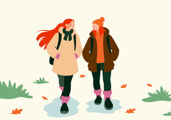 Female friends wearing warm clothes and walking in park
