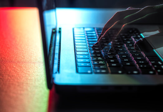 Young hacker typing on laptop at desk