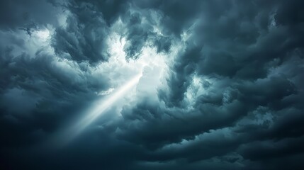 Obraz premium Dramatic light beam piercing dark stormy clouds.