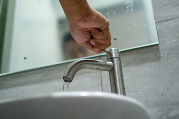 Man hand opening the water tap. Turning on the faucet in bathroom.