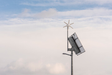 Na zdjęciu widać instalacje słoneczno-wiatrową, w tle jest zachmurzone niebo. Turbina produkuje prąd zawsze gdy wieje wiatr. © Marcin