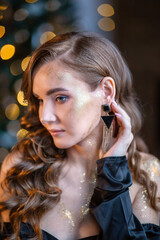 Naklejka premium beautiful girl celebrates christmas on the background of a christmas tree
