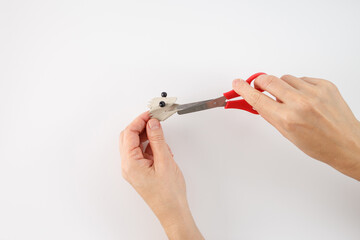 using a pair of red-handled scissors to cut. a crafting or DIY activity, part of a larger project, making lizard craft for kids,