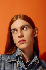 Fototapeta premium Emotional expression of a young man with long red hair against an orange background