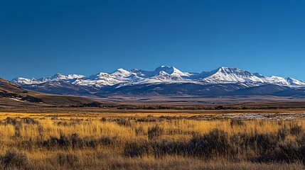 Obraz premium A panoramic view of a snow-capped mountain range under a clear blue sky