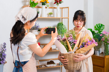 A florist taking a photo of a bouquet while another florist admires the creation, showcasing...