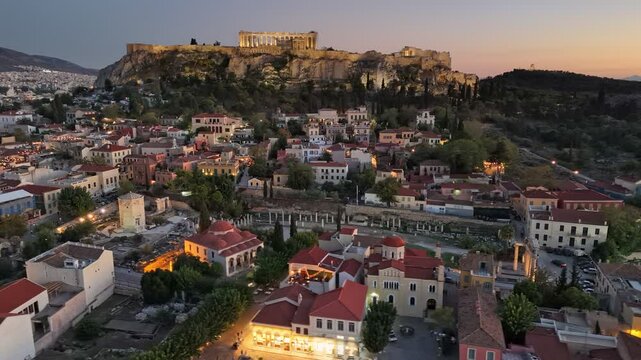 Beautiful sunset view of Athens with the Acropolis illuminating the skyline and charming rooftops of the city. Athens old town aerial shot. Parthenon on the hill with illumination
