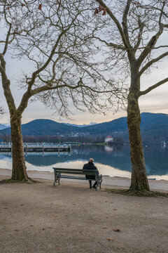 ein &auml;lterer Mann sitzt alleine auf einer am Bank am See, Symbol f&uuml;r Einsamkeit, Alter