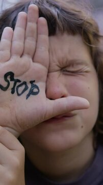 A child expresses a powerful message against violence and abuse by showing a hand with the word 'stop' written on it, advocating for change in society. Abuse, domestic violence protection concept
