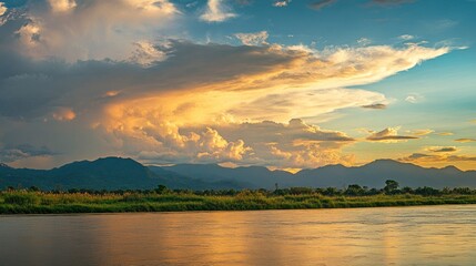 Fototapeta premium A serene landscape of the Mekong River, surrounded by mountains and countryside in Nong Khai, Thailand. The amazing sky above adds depth and warmth to this picturesque view.