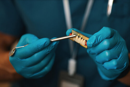 Close-up of dental practitioner handling dental tools with precision. Practitioner wearing blue gloves while holding MECOS dental instrument