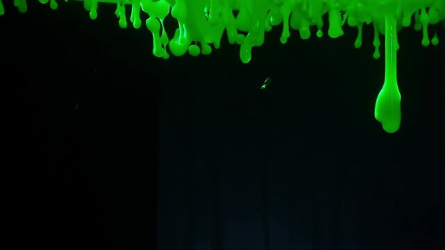 Dripping green slime with blobs on black background, seamless border pattern, radioactive liquid with drops flowing, vertical 4k video. Glowing green liquid dripping down black background