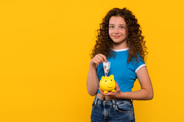 Smiling girl holding a piggy bank and saving money. The concept of financial education for children...