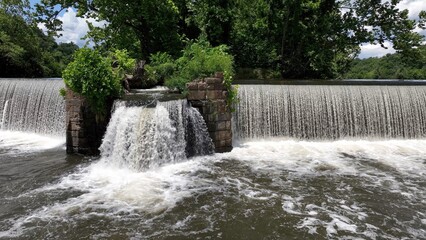 Beautiful waterfall on warm summer day on James River at Lynchburg, VA historic southern town green trees blue sky with clouds