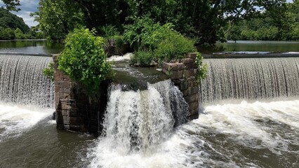 Beautiful waterfall on warm summer day on James River at Lynchburg, VA historic southern town green trees blue sky with clouds