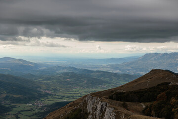Fototapeta premium vista dettagliata dall'alto di una vasta zona ricca di catene montuose e collinari nella Slovenia occidentale, di pomeriggio, in autunno, sotto un cielo nuvoloso