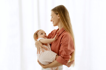 Happy mother holding adorable baby girl and lull daughter to sleep, woman embracing cute kid with...