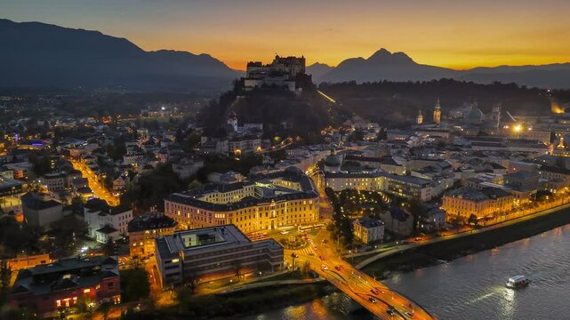 Beautiful sunset over Salzburg showcasing historic architecture and fortress. Fly over illuminated old town of Salzburg, Austria