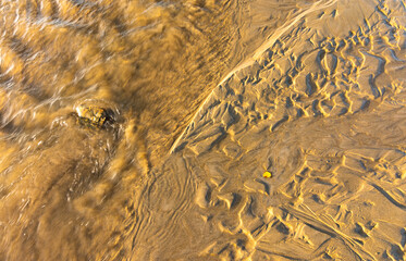 Detalle de textura de un riachuelo en una playa de arena