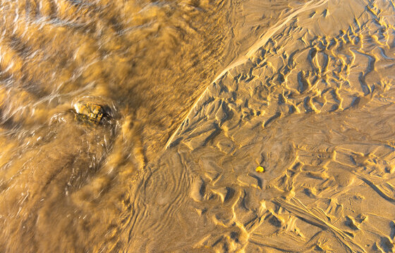 Detalle de textura de un riachuelo en una playa de arena