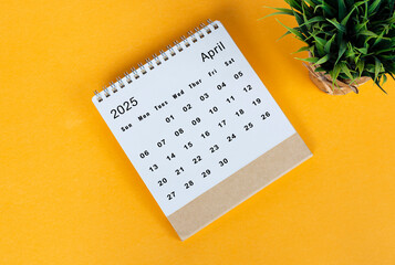 April 2025 desk calendar on yellow background. Directly above. Flat lay