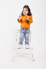 Little girl on a chair clapping her hands smiling on white background