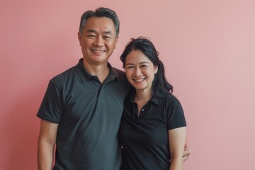 Obraz premium Portrait of a smiling asian couple in their 40s wearing a sporty polo shirt in solid pastel color wall