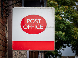 A red and white post office sign hanging from wall.