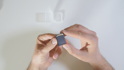 Close-up of a photographer carefully holding a micro sd memory card, showcasing the essential tool...